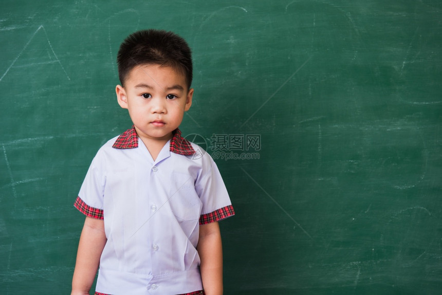 快乐的亚洲可爱小孩男从幼儿园的稚穿着学生制服的微笑在绿色学校黑板上第一次到学校教育概念摄影棚拍图片