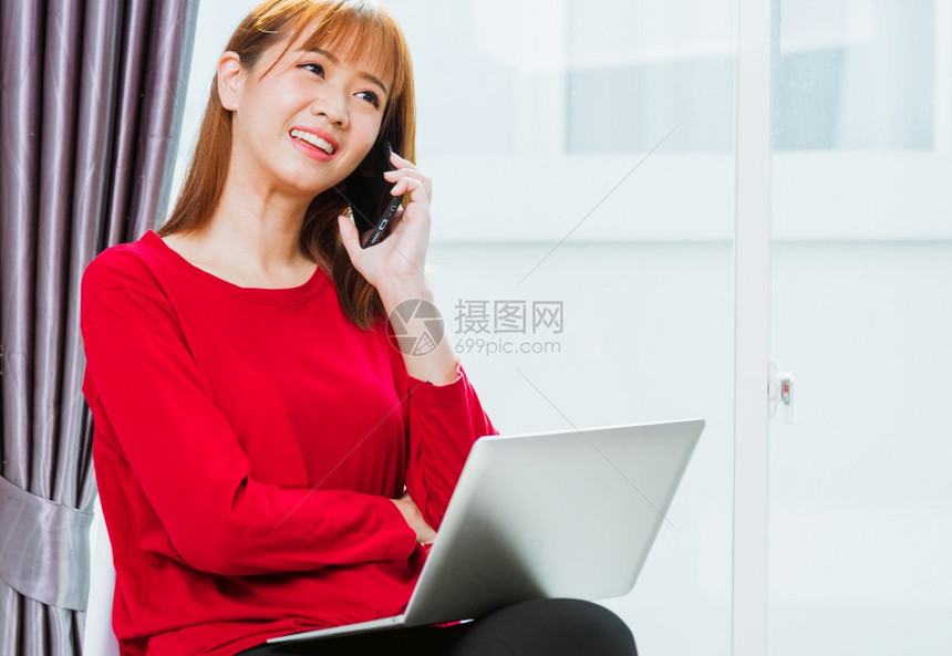 在家工作的概念亚洲美丽的年轻女子微笑学生坐在椅子上用移动电话主任在家庭办公室使用笔记本电脑工作时团队合图片