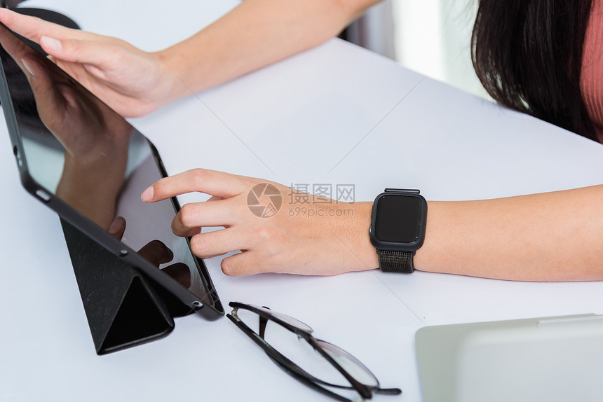 在家工作快乐亚洲年轻商业女人使用手指触摸屏幕现代数字智能平板电脑她戴着智能手表图片