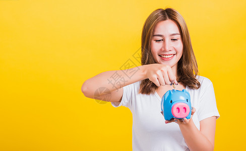 向小猪银行扔硬币寻找小猪银行摄影棚在黄色背景上被孤立图片