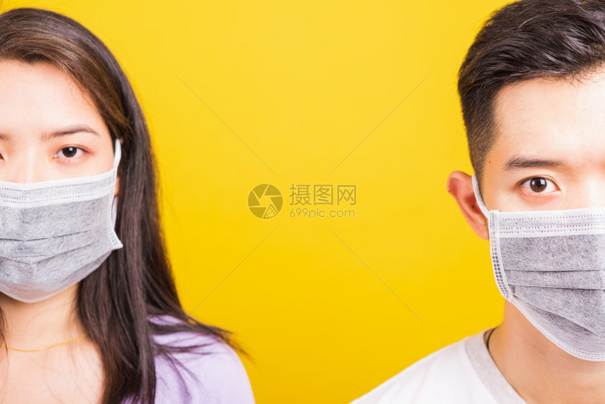 亚洲美丽女和英俊男子身戴防护面罩保防止冠状寻找相机摄影棚拍攝室黄色背景与复制空间隔绝COVID19或冠状概念图片