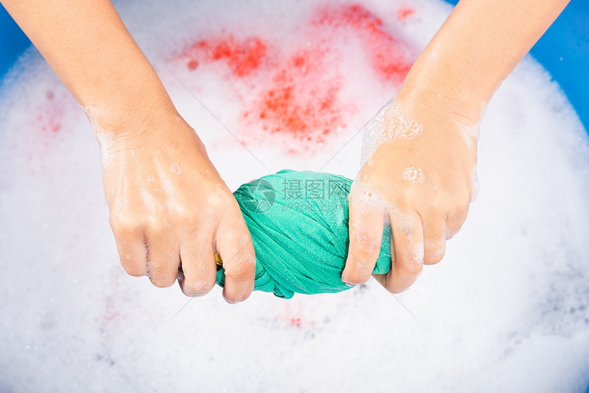 紧闭的亚洲年轻女在盆地用手洗彩衣物女用洗涤剂挤的湿布有水中肥皂泡工作室拍摄背景洗衣概念图片