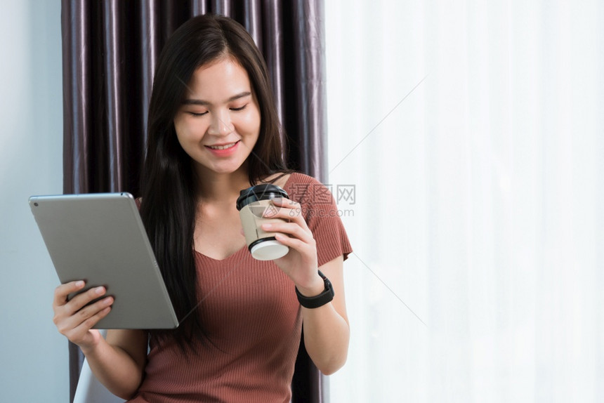 在家工作快乐亚洲年轻商业女青微笑视频会议电话或用现代数字智能平板电脑面对时间她用手指触摸屏幕图片