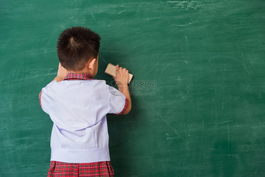 可爱小男孩穿着校服站在绿色校黑板上微笑图片