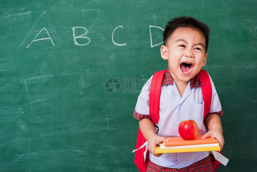 可爱小男孩穿着校服站在绿色校黑板上微笑图片