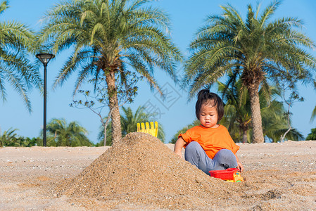 孩子玩沙子亚裔泰国快乐可爱的小快乐女儿孩在夏季日与影印空间在户外热带海滩用沙子挖玩的具背景