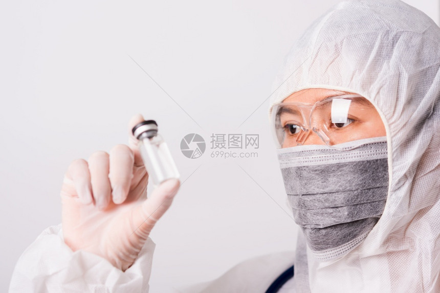 身着个人防护设备制服女医生注射药物和瓶疫苗图片