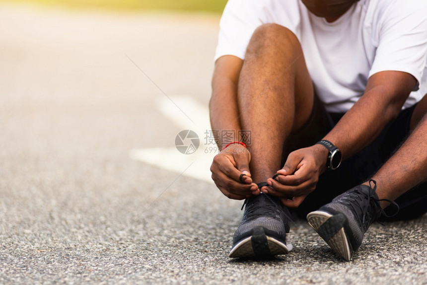 近亚洲运动赛跑的黑人穿着手表坐他努力尝试鞋带跑准备慢和在户外街头健康公园跑步并配有复制空间健康运动锻炼概念图片