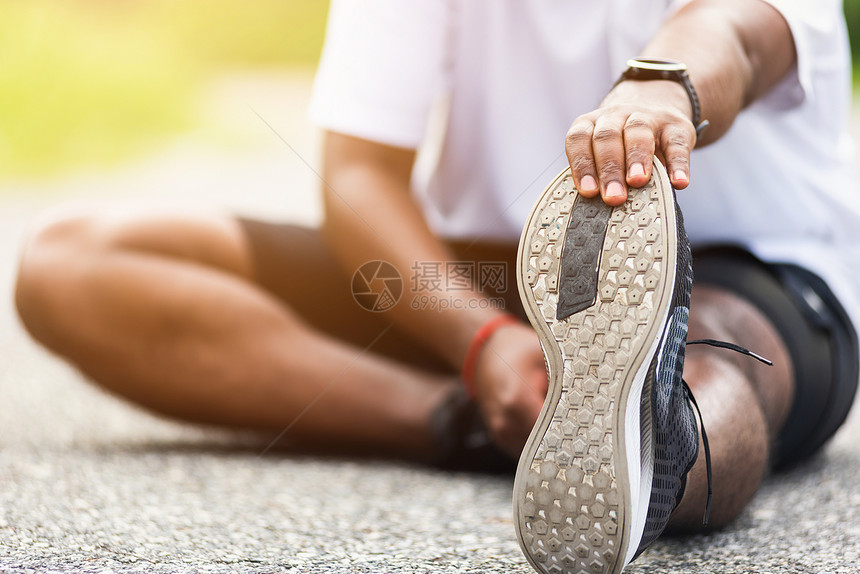 亚洲年轻运动员赛跑选手黑人穿着表坐拉脚伸腿和膝盖然后在户外街头健康公园跑在锻炼前健康图片