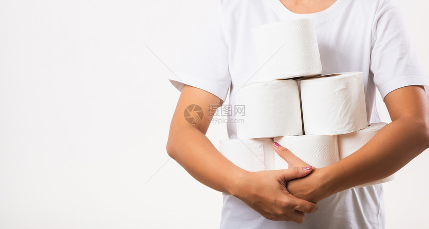 亚洲年轻女子在科罗纳隔离的仓库里装上卫生纸进行家庭恐慌胸前手持许多卷卫生纸的女白背景孤立的演播室图片