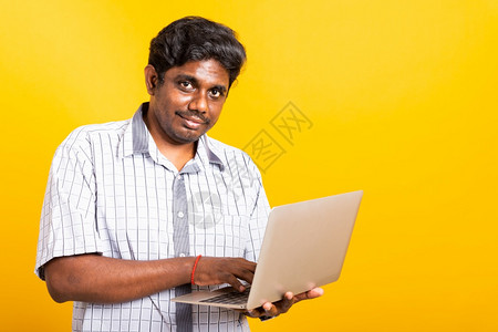 亚洲快乐肖像年轻的黑人男子微笑着站穿衬衫拿笔记本电脑打字图片