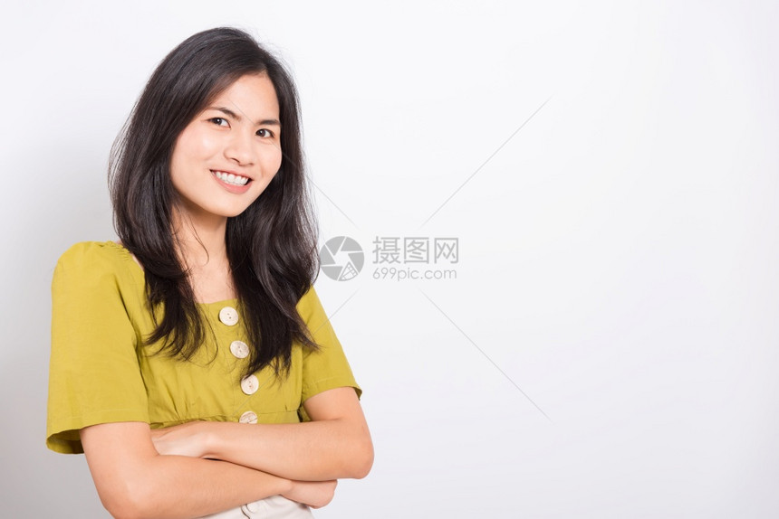 站在白牙边微笑着的亚洲美丽年轻肖像女她横跨双臂看着摄影机拍白色背景的摄影棚照片图片