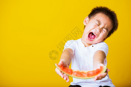 快乐的亚洲儿童或孩子可爱的小男孩笑玩着切开西瓜新鲜食物拍片室摄孤立在黄色背景上健康食物和夏季概念背景图片