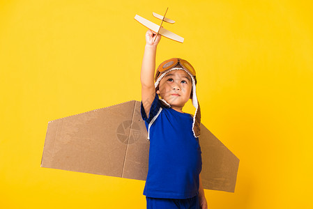 男孩戴着飞行员帽子玩着纸板飞机高清图片