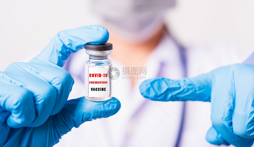 身穿制服的亚洲女医生或护士身戴面罩的手套在实验室中用瓶状科罗纳疫苗和子指着上面贴有COVID19CoRONAVIRUSVACCI图片