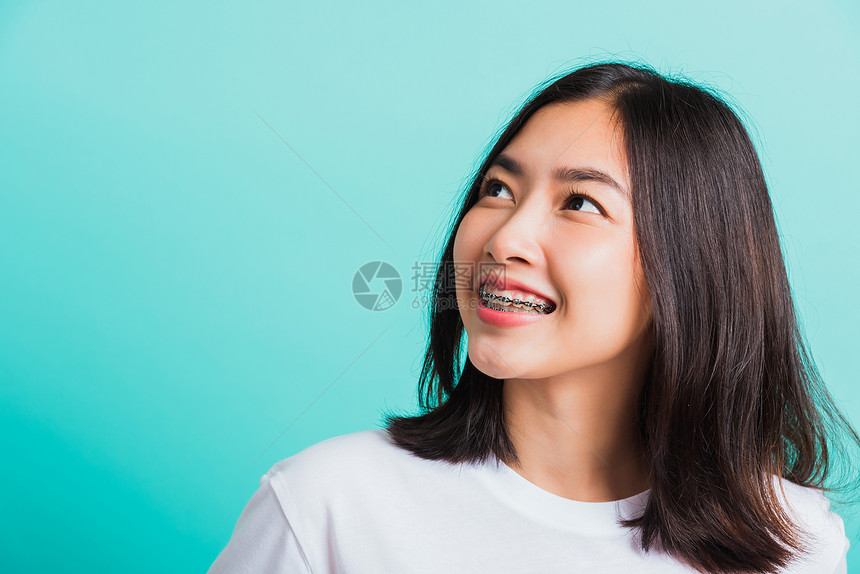 近距离身的亚洲年轻美女微笑牙齿上有套笑着看外边的空间摄影棚拍隔着蓝背景孤立的电影室药物和牙医女口腔概念图片
