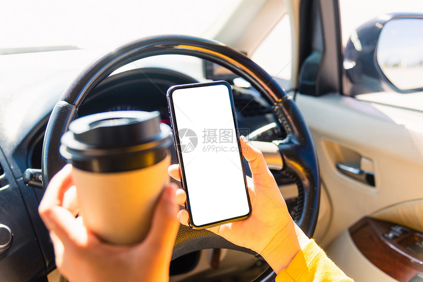 亚洲妇女在汽车内喝热咖啡杯并使用智能手机空白屏图片