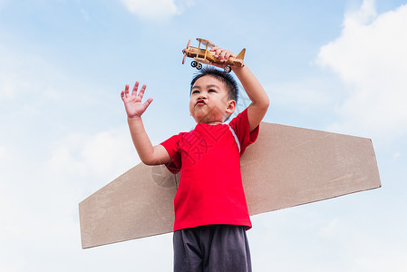 纸板机翼男孩拿着飞机玩具玩耍背景