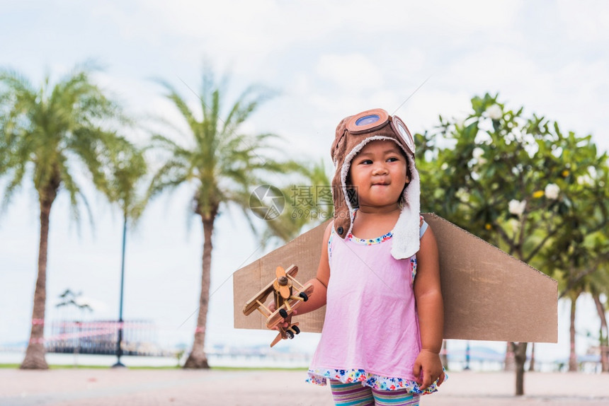 小女孩戴着飞行员帽子玩着纸板飞机图片