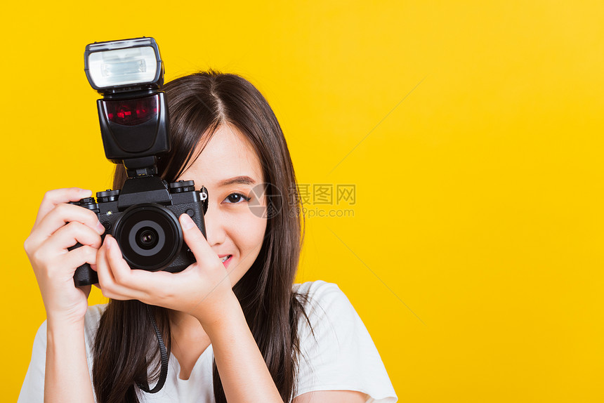 亚洲美丽年轻女摄影师笑容的喜悦拍摄照片并透过古老的数码无镜照摄影机拍影棚图片