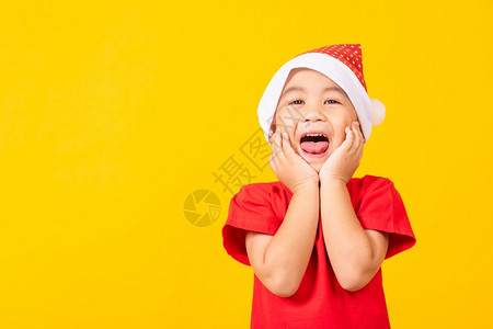身着红色圣诞老人帽子的孩们震惊和讶地握手面对圣诞节或新年快乐的概念图片