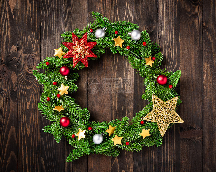 带有装饰品的圣诞花圈树壁枝的顶部视图滚动在一个圆圈中黑桌木本底的装饰明星中滚动新年节庆装饰概念图片