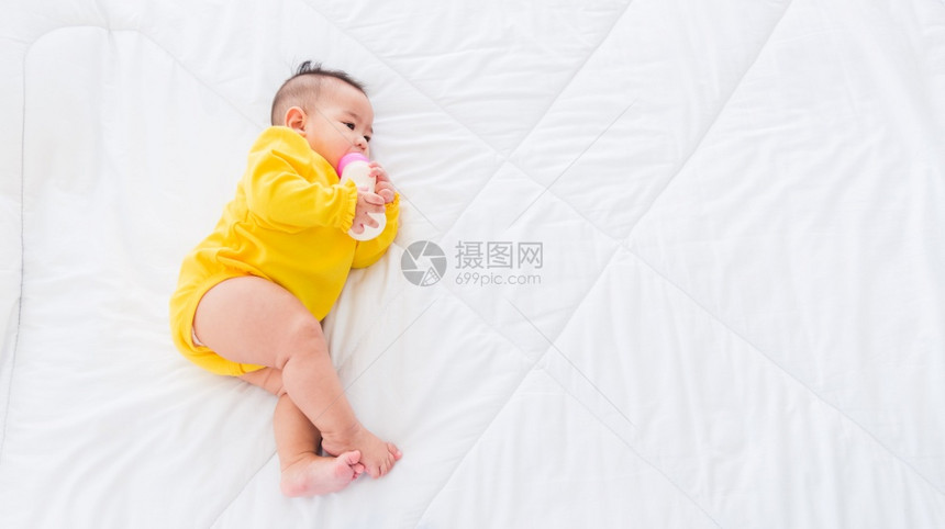 婴儿躺在床上拿着一瓶牛奶婴儿喝图片