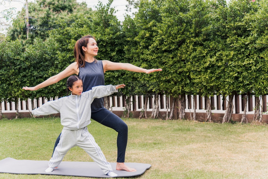 亚洲年轻母亲与女儿一起练习瑜伽在冥想室外与女儿一起在自然的绿草地上做一个野外花园公家庭运动和健康生活方式的锻炼图片