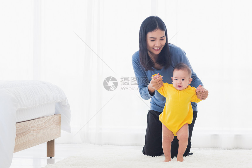 亚洲小女孩步入第一学习与妈一起走路帮助支持可爱的不稳定步行幼儿在卧室的家中图片
