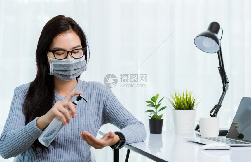 身戴面罩的亚洲年轻女商人身戴面罩在家办公室工作用笔记本电脑柜台隔离疾病冠状毒图片