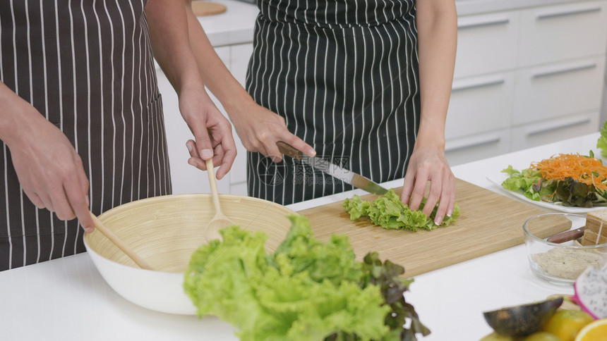 亚洲美丽家庭快乐的一对夫妇妻在家里厨房一起煮菜沙拉男人把蔬菜混在一起用个女杯子煮蔬菜健康的食物概念图片