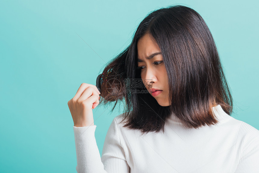 年轻的亚洲美女对梳子和问题头发心烦意乱图片