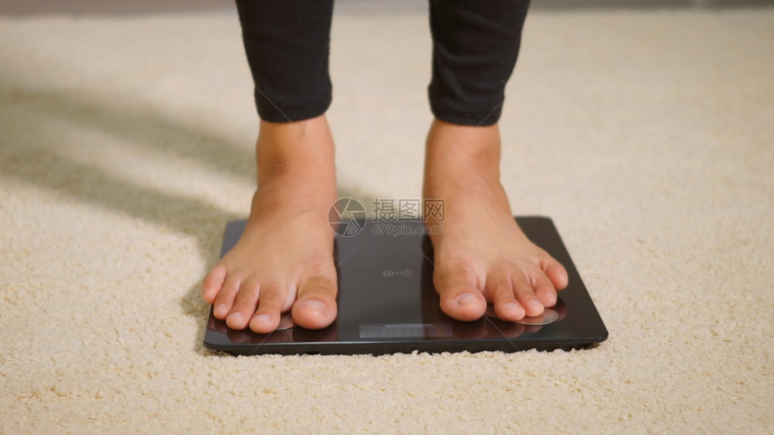 亚洲青年女子腿脚站在电压地板上女在家工作起居室女站在数字称重机上健康减控制概念慢动作图片
