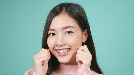 青春的亚洲年轻美女微笑着在蓝色背景孤立的牙齿上佩戴硅酮或口服牙膏用可移动的牙套后保留工具背景图片