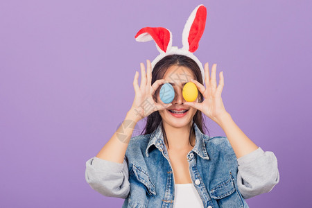 头戴兔子耳朵和手拿两个彩色鸡蛋微笑的女士图片