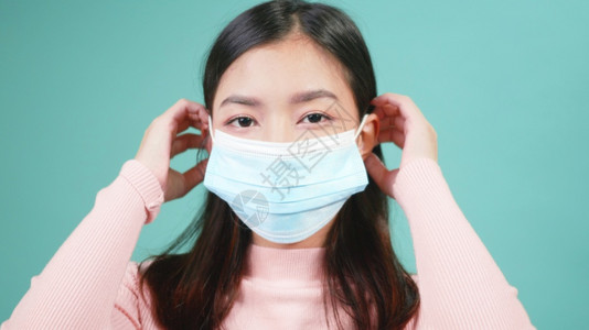 身戴抗防护面罩的年轻亚洲快乐美丽女佩戴无菌的医学面具图片
