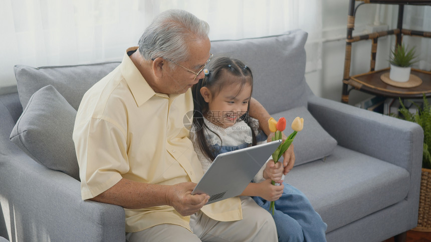 外祖父和他的孩子在客厅沙发上看数字平板新闻图片