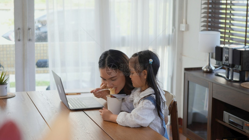 亚裔家庭年轻母亲在笔记本电脑上工作图片