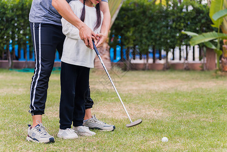 亚洲年轻父亲支持教育训练女儿打完美的高尔夫同时站在自然界的高尔夫球场上在野外花园公家庭户外运动概念中一起站在背景图片