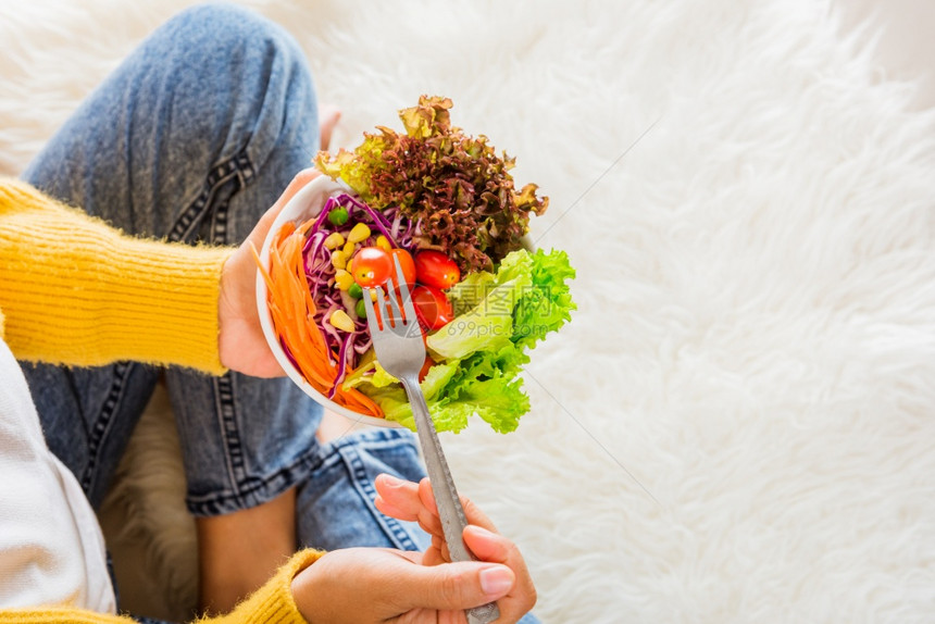 一位年轻女子在碗里吃新鲜沙拉饭素食菠菜清洁去毒健康食品概念图片
