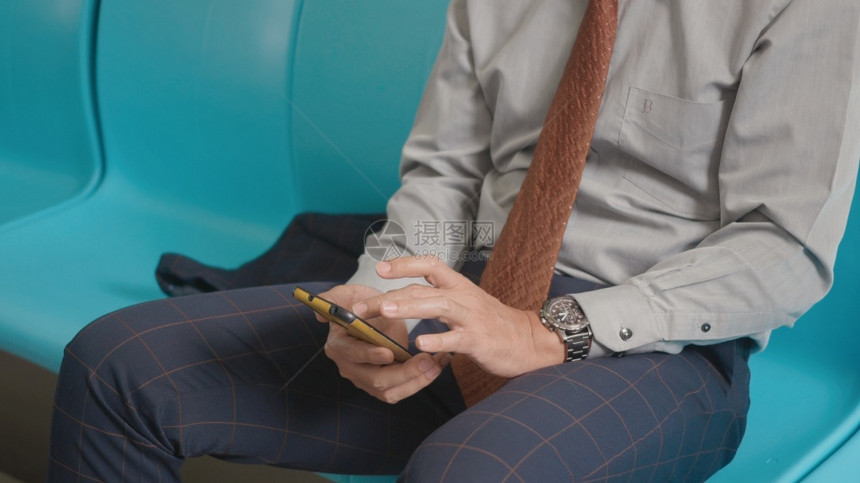 坐在座椅上的近身商人使用现代智能手机在互联网上检查电火车新闻交通客中年男子在手机上发短信图片