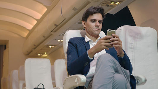 青年男子乘客在飞机上使用智能手机图片