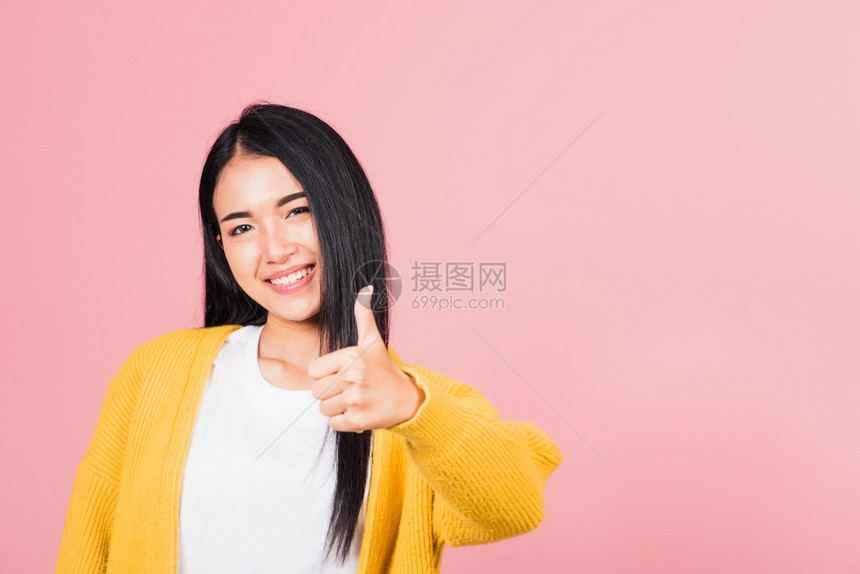 亚洲美丽的漂亮年轻女微笑她站立手指拇OK签名同意摄影棚拍孤立在粉红背景泰国女成功如手指势复制空间图片