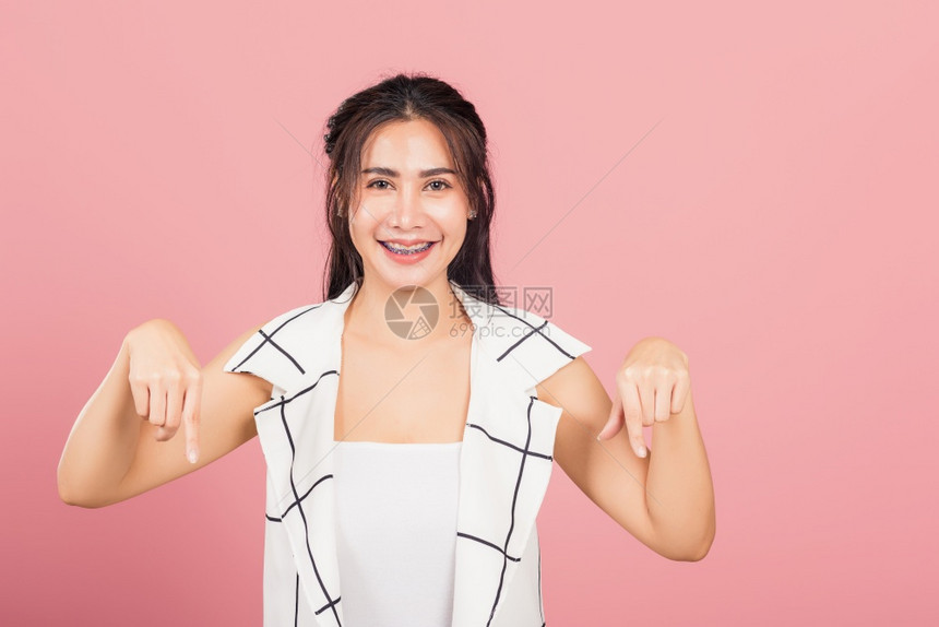 亚洲美貌丽的年轻女子不快乐消极的手势显示指拇低下或不喜欢牌子摄影棚拍在粉红背景上被孤立泰国女拒绝与复制空间不同图片