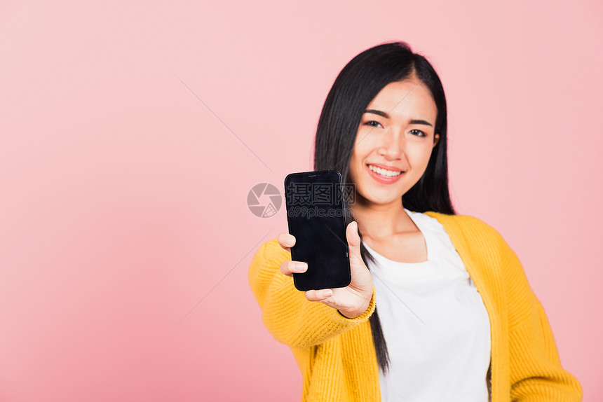 带着空白屏幕手机演播室拍摄在粉红背景上被孤立泰国女展示智能手机空屏幕间图片