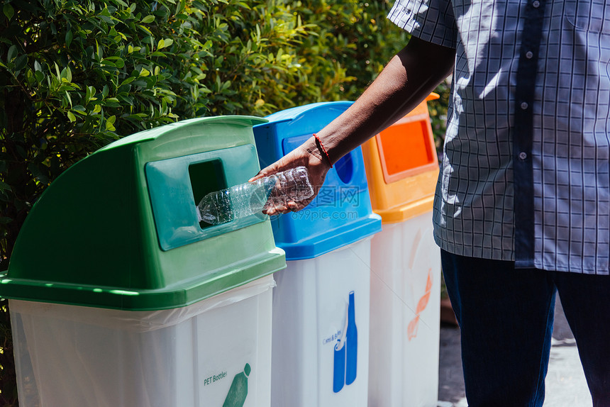 有选择焦点封闭了黑手在回收垃圾或桶中扔空塑料水瓶环境再循概念图片