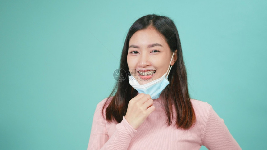 亚洲美丽的人脱下保护面罩微笑露出牙齿上的硅酮整保留剂女除去无菌的医学面具快乐地战胜冠状图片