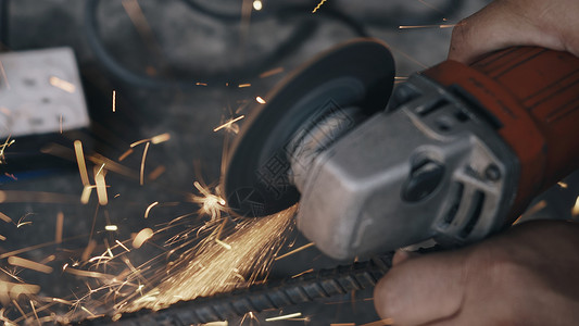 使用电轮磨机和切割钢铁结构的工人男子从生产业的研磨轮中燃起火花背景