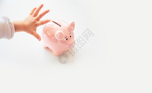 宝贝银行素材婴儿手在粉红小猪银行中储蓄亮白孤立的背景复制空间文本婴儿手在粉红小猪银行中储蓄背景