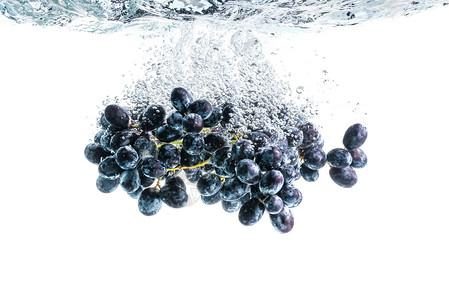 一串红葡萄溅入晶莹剔透的水中健康食品一串红葡萄溅入晶莹剔透的水中背景是白色的背景